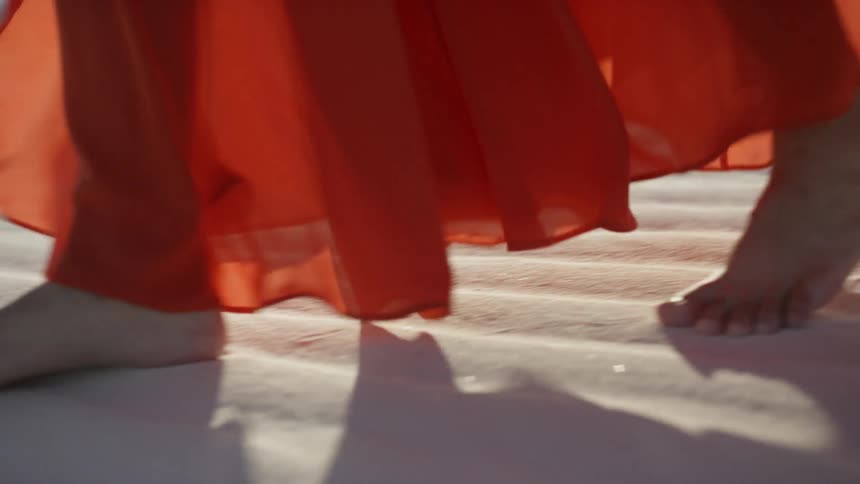 A woman in a full length dress walking on sand dunes