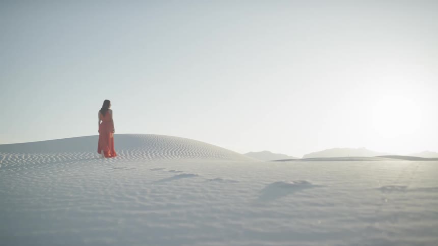 Woman leaves footprints as she crosses white desert sands