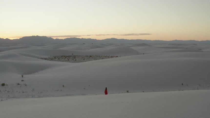 Woman in red dress walking across the snow in the distance