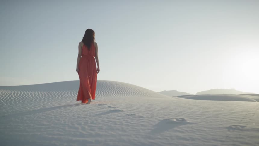 A woman is walking through a desert area