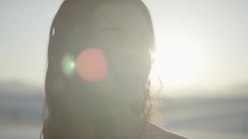 Brunette girl looks sideways while the sun goes down in the desert