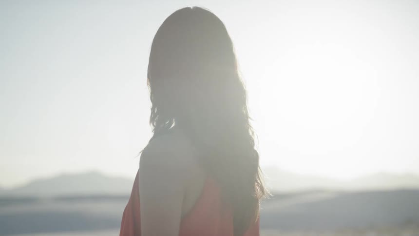 Young woman in a red dress looking out at horizon