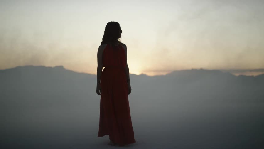 A woman walking in a smoky desert at dawn