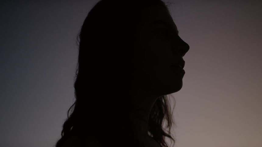 A woman stands in the darkness