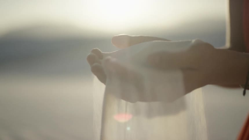 A woman picks up sand and lets it fall through her fingers