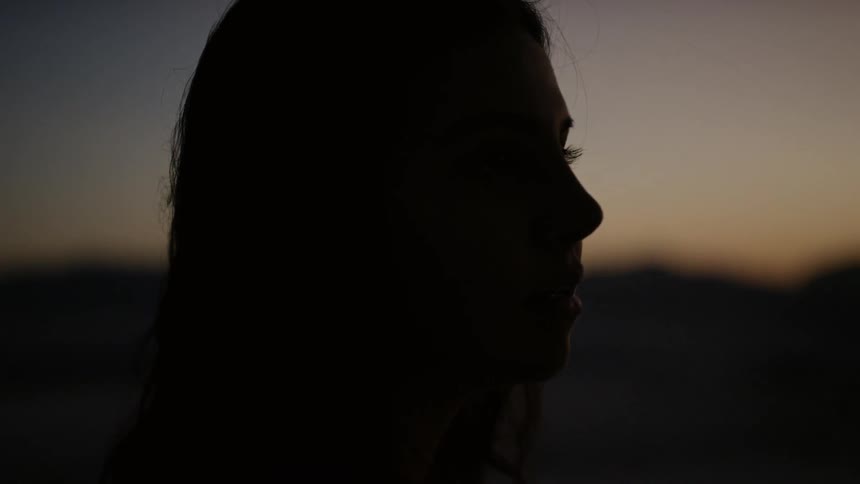 A woman standing outside as the sun sets