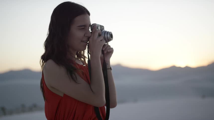 A young woman stands on the beach and takes pictures