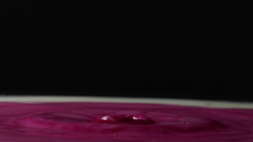 A drop of purple creates ripples and a splash when it hits the surface