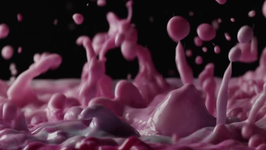 Colored liquid starts to splash form bubbles and then becomes calm again