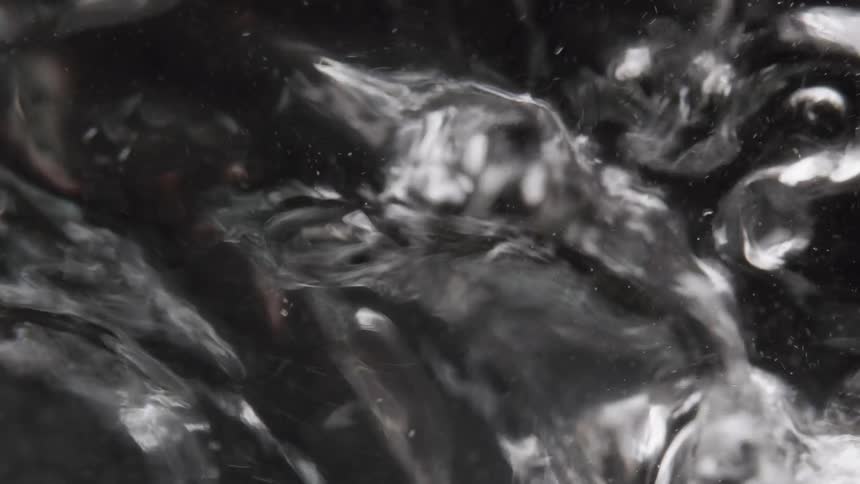 Bubbles form in water in front of a dark background