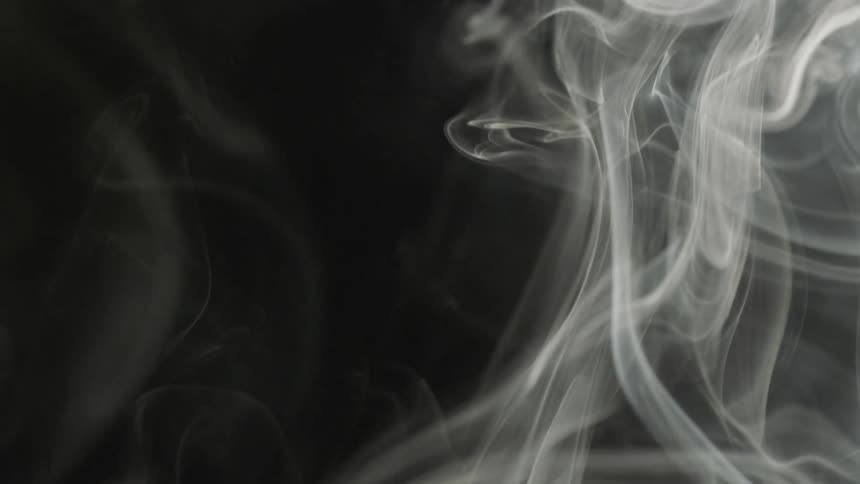 White smoke curls in the air against dark background