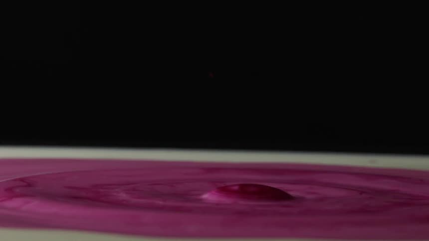 A drop going into a pink liquid