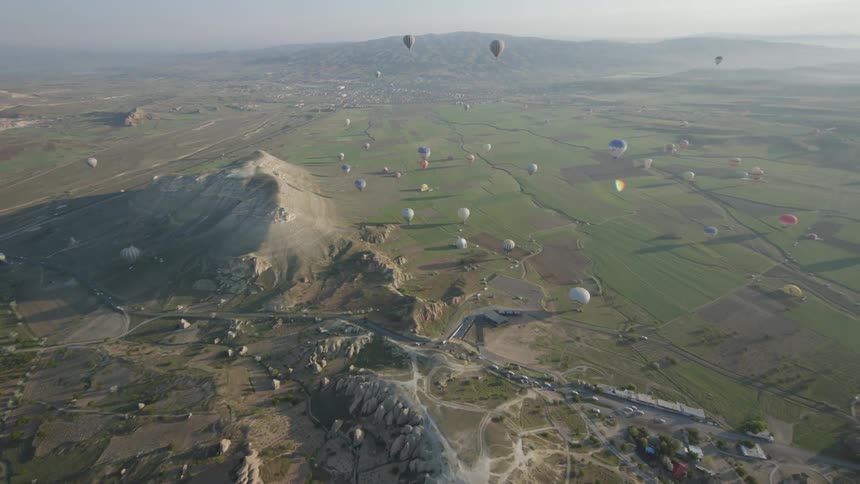 An aerial view of hot air balloons in the sky is displayed