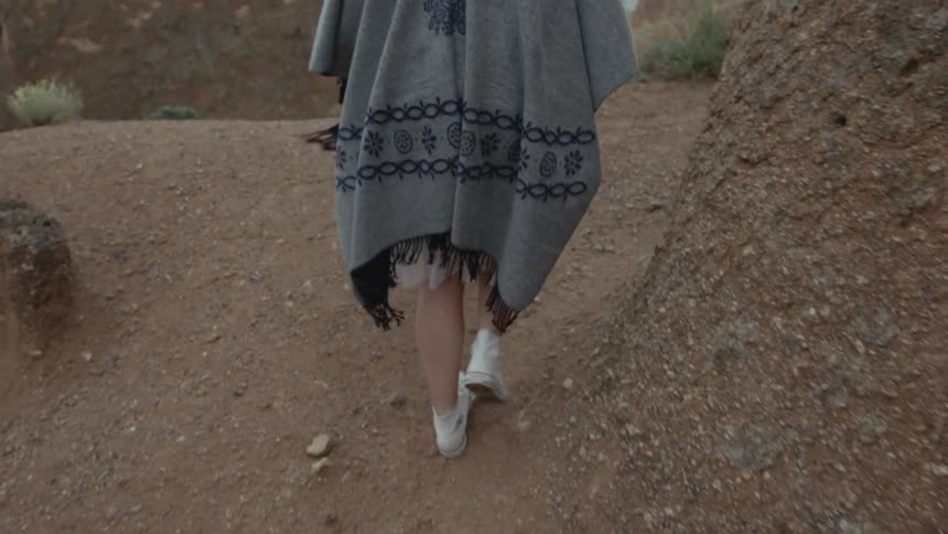 A woman walks outside with a blanket over her shoulders