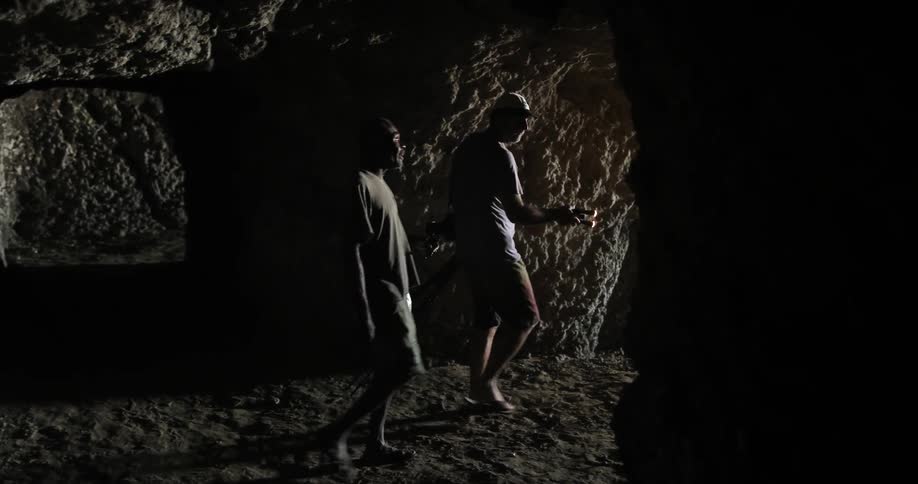 Two men are traveling in a dark cave