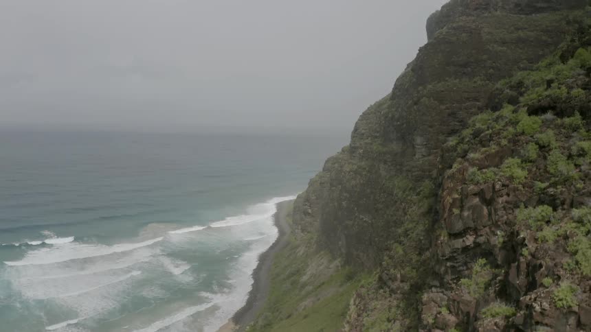 Waves crash onto the shore of a tall promontory