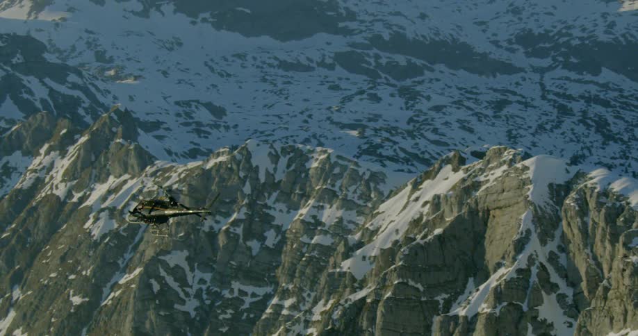 A helicopter flies over the mountains