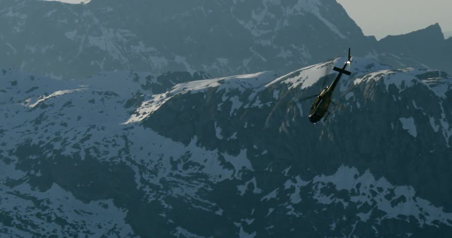 A helicopter flying downward with mountains in the background