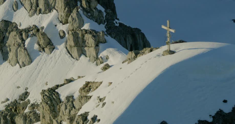 A cross on the top of a snowy mountain