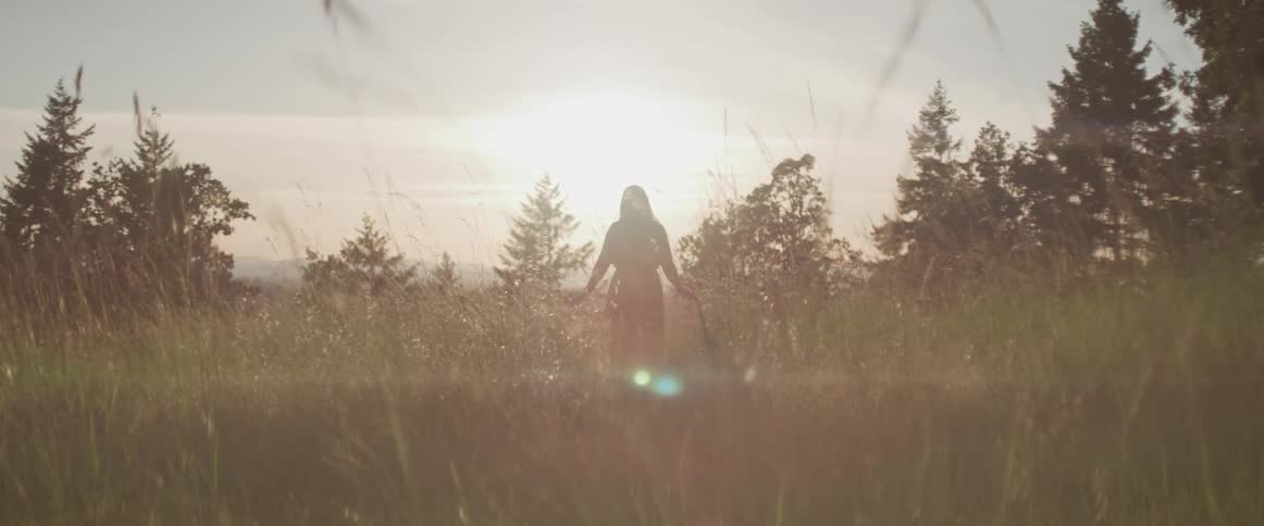 A woman is walking in a grass field