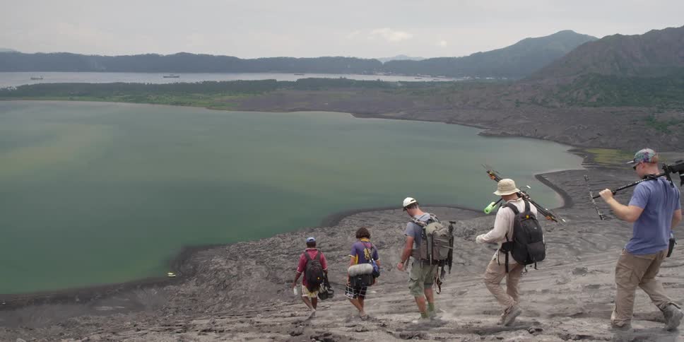 Men approach a lake with equipment in tow
