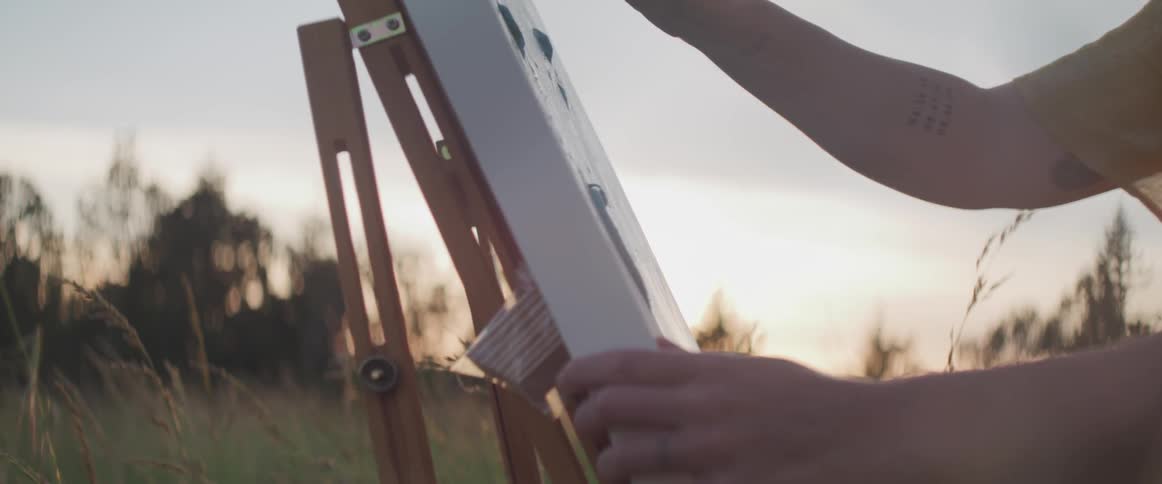 A person paints in the tall grass