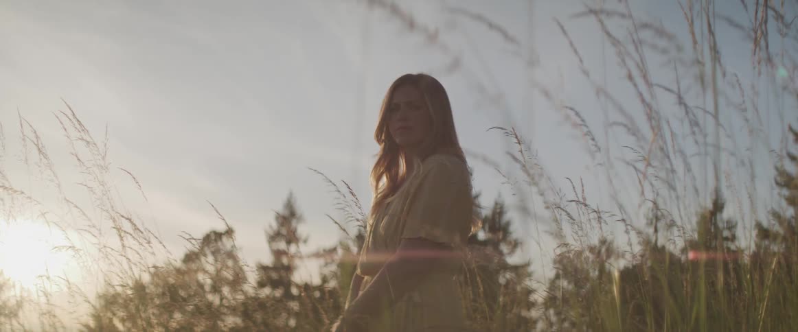 A woman stands in a grassy field