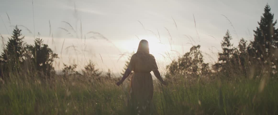A woman is walking through the tall grass