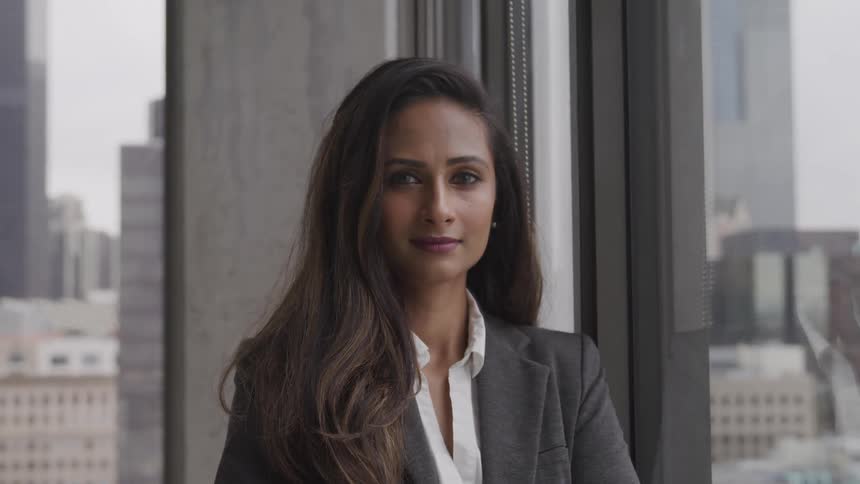Brunette businesswoman stands next to the window in the office