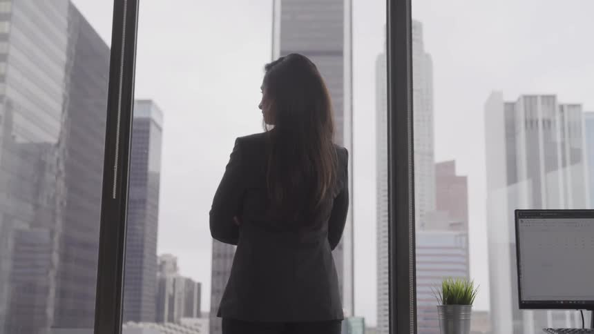 Woman with crossed arms looking out window from an office building