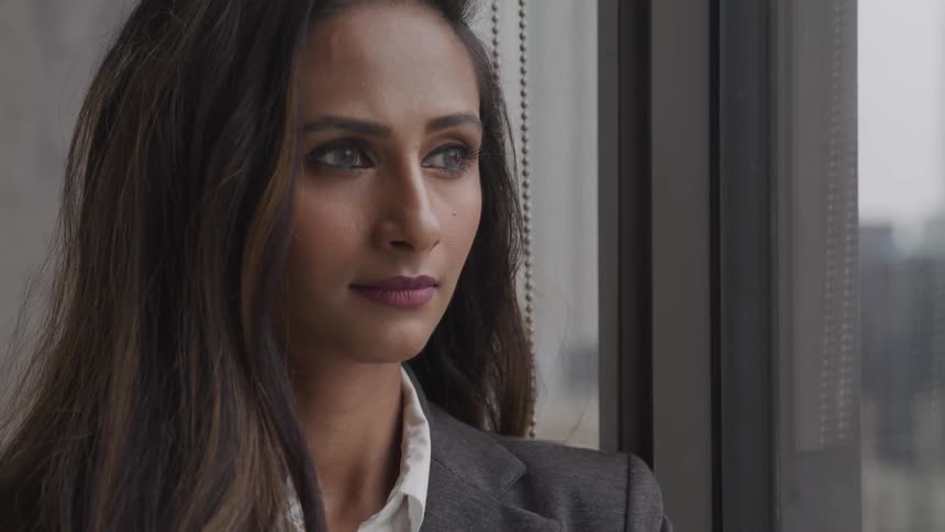 Woman blinks her eyes as she looks out a window