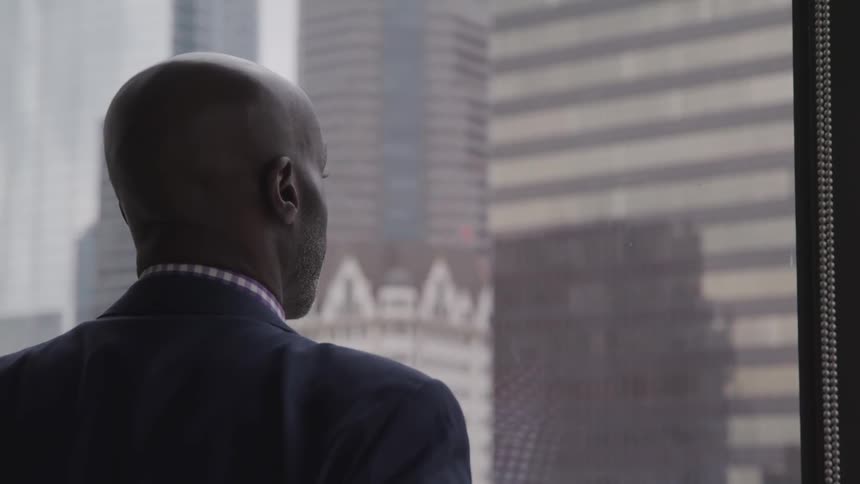 A black man looks out his office window