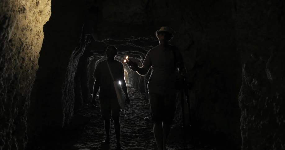 Explorers Walking Through Cave