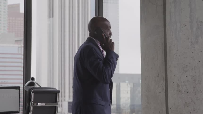 A black man talks on the phone in an office