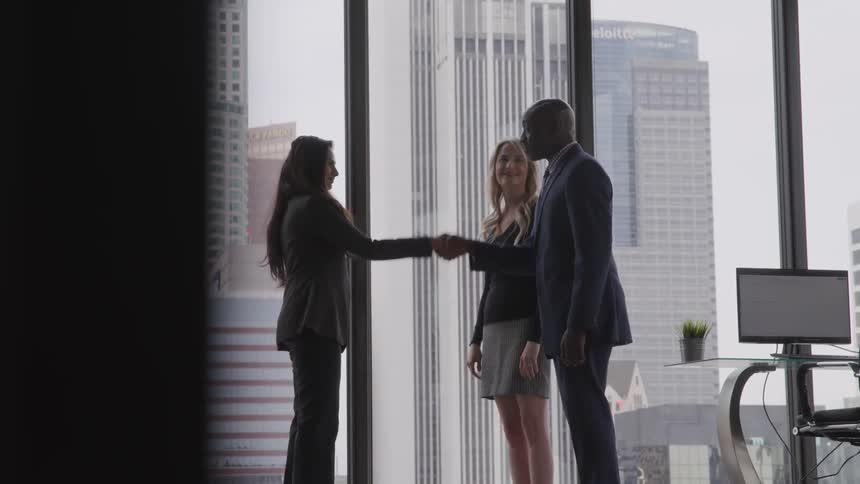 Three people are shaking hands in an office building