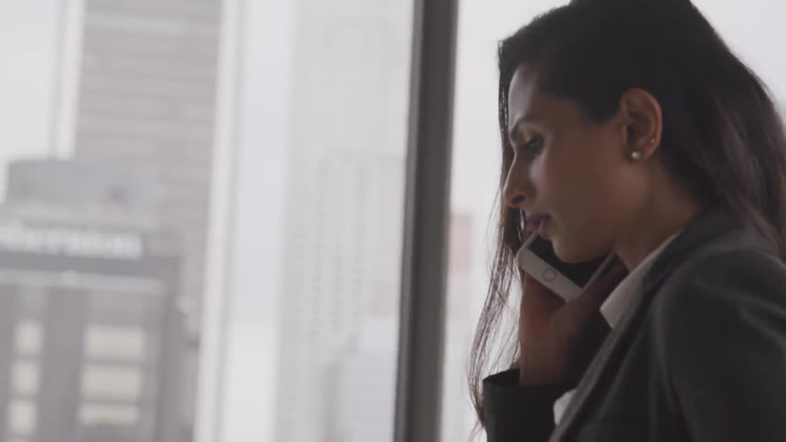 Brunette businesswoman walks and talks on the phone in the office