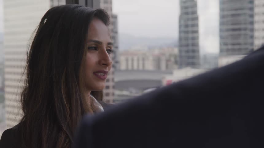 A woman stands in front of a window and talks with a man