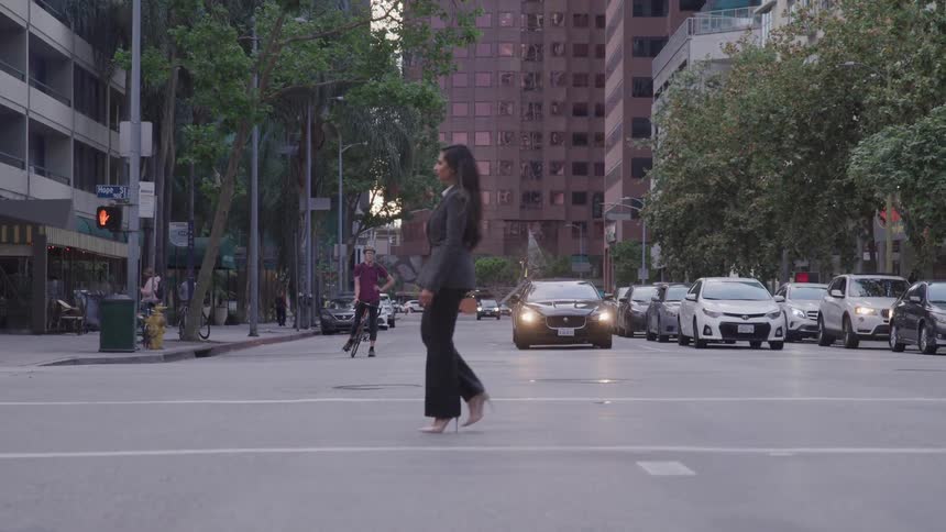 A woman walks in the crosswalk to cross an intersection