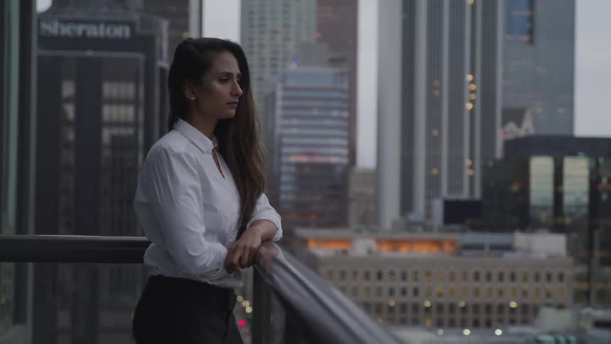 A woman is standing on the balcony looking at the city