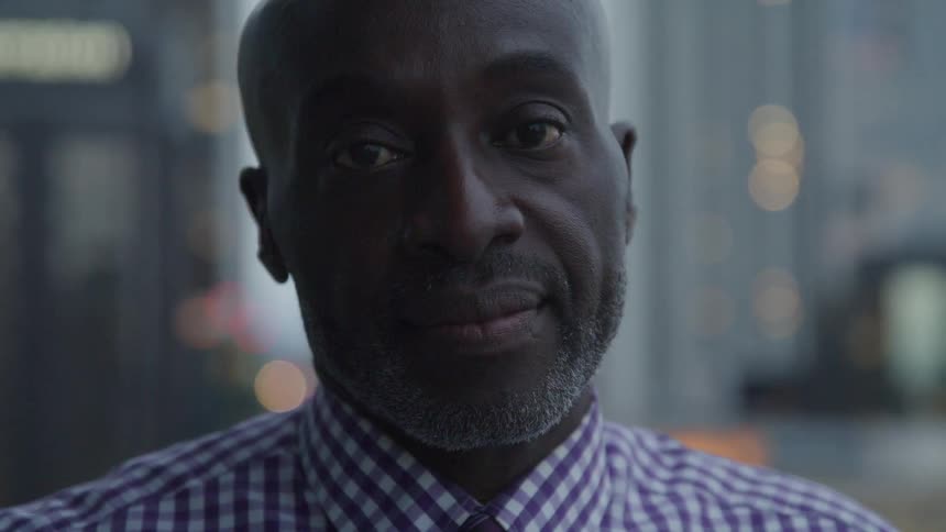 Bald headed black businessman looks at the camera wearily in the office