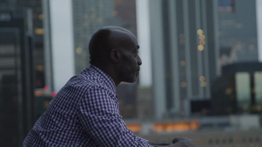 A man standing staring off in the distance with buildings in the background
