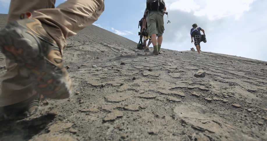 A group of people are climbing up a hill on a cloudy day