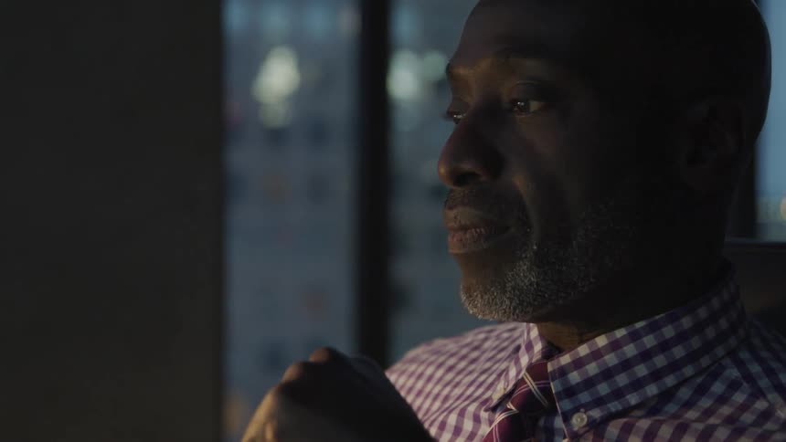 A black man sits in his office and looks ahead
