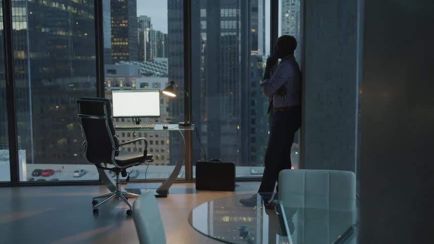 A man stands against the wall of his office
