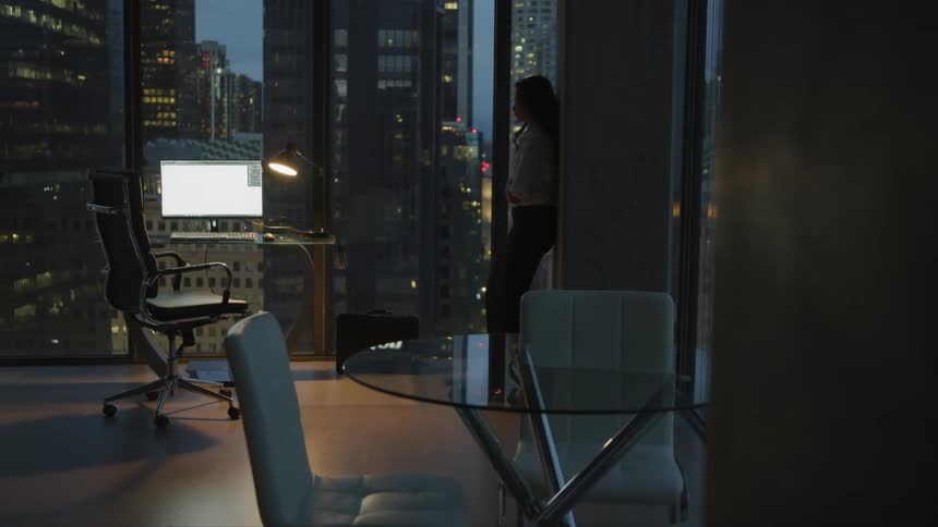 A woman standing by a window at dusk