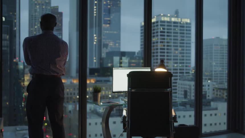 A man staring at the dawn sky from the office