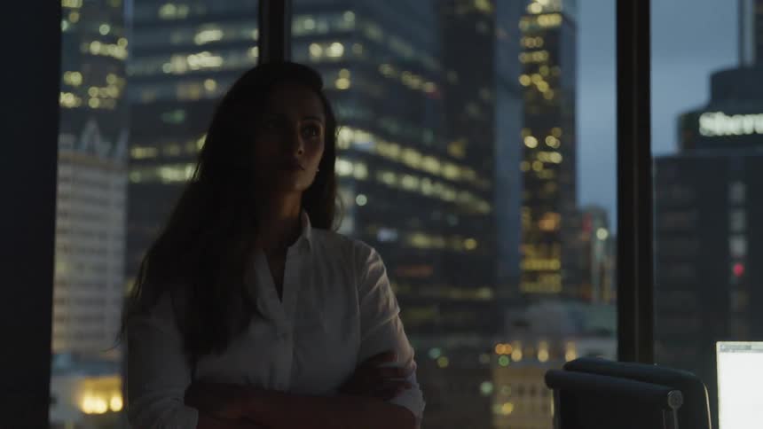 Business woman walks in the office and tall buildings in the background at dusk