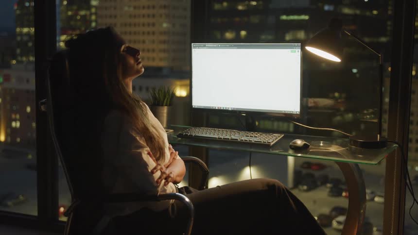 A woman sitting down with her eyes closed in front of a computer