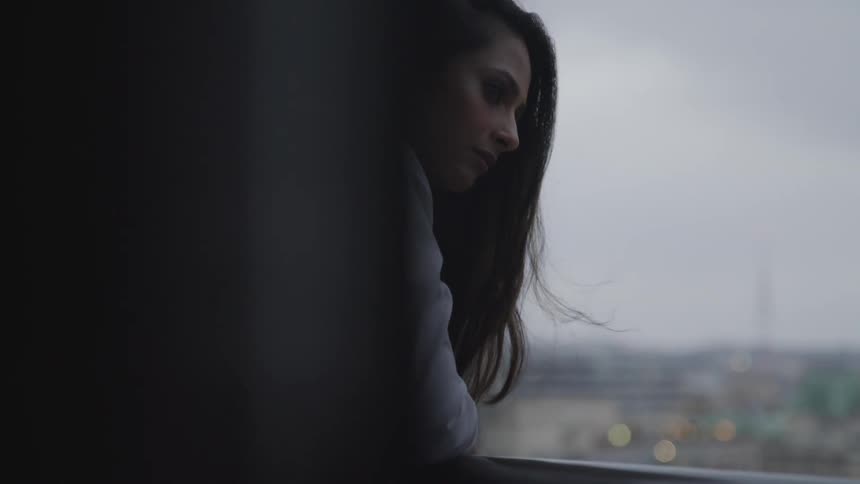 Brunette businesswoman rests her elbows on the banister on the balcony of the office