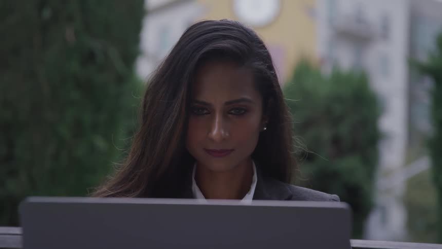 A woman is on a laptop while sitting outdoors